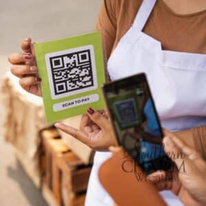 A vendor holding a bright green "Scan to Pay" QR code sign while a customer uses their smartphone to make a payment, highlighting a seamless checkout experience.