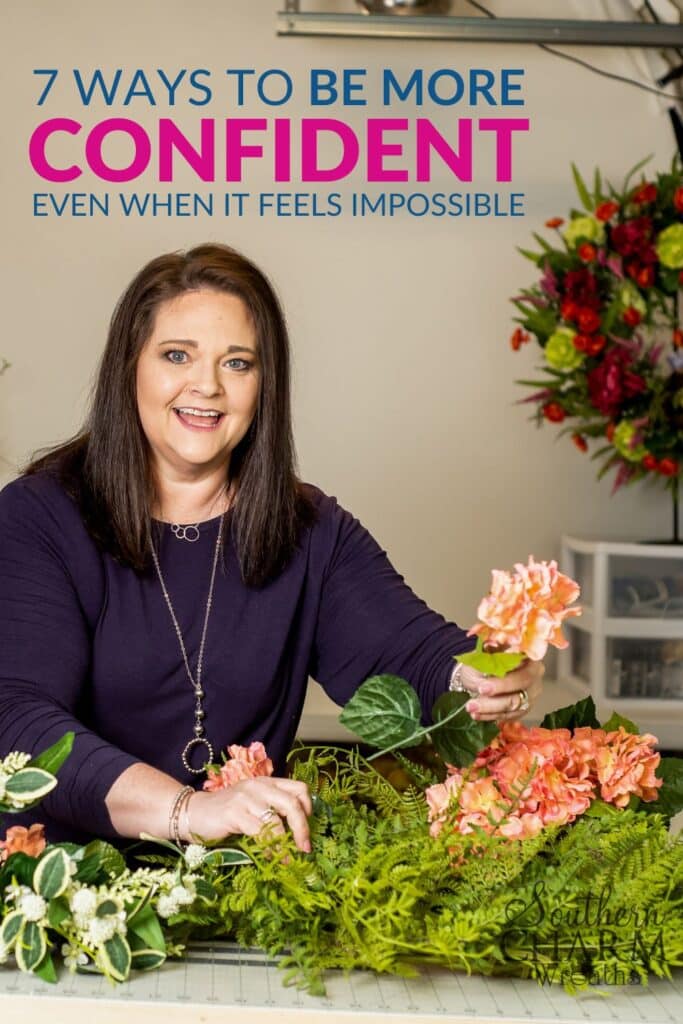 A smiling woman arranging vibrant silk flowers, representing the confidence and creativity encouraged in the blog post '7 Ways to Be More Confident.