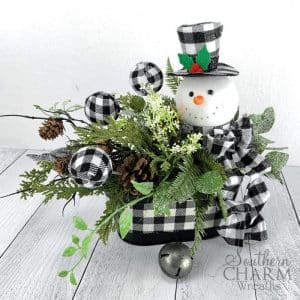 Tabe arrangement with buffalo plaid ornaments and snowman, pinecones and greenery