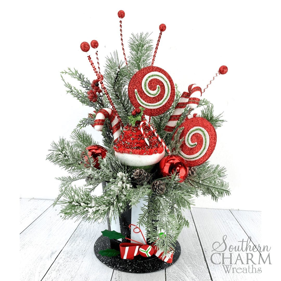 Christmas table arrangement with snowman hat, evergreens, and large candy ornaments