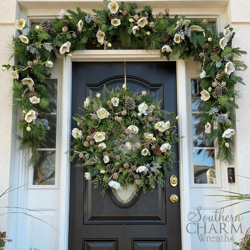 Winter front doorscape with evergreen garland, silk flowers, and pinecones.