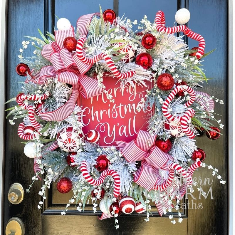 Merry Christmas flocked wreath hanging on door with Merry Christmas y'all sign attached. 