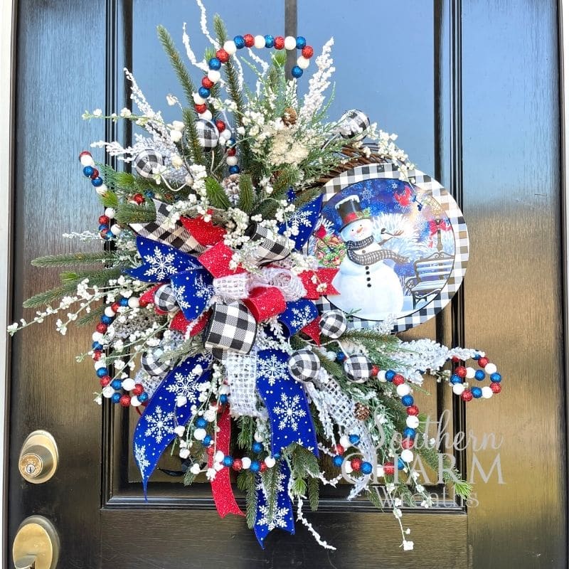A blue and white snowman wreath with silk flowers