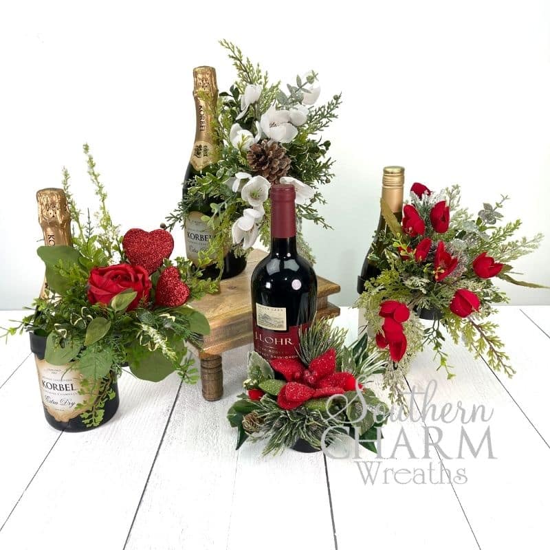 Four wine bottle bouquet arrangements with red flowers