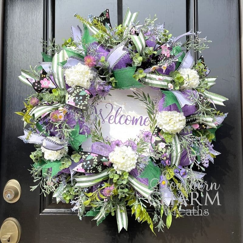 green and lavender deco mesh wreath on black door with welcome sign