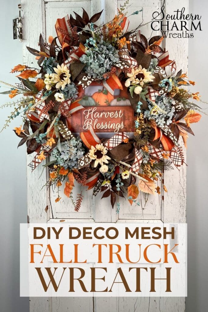 Handmade fall wreath made with deco mesh, ribbons, pale blue hydrangeas, sunflowers, and a rustic orange truck sign that says “Harvest Blessings.” Perfect for autumn front door décor.