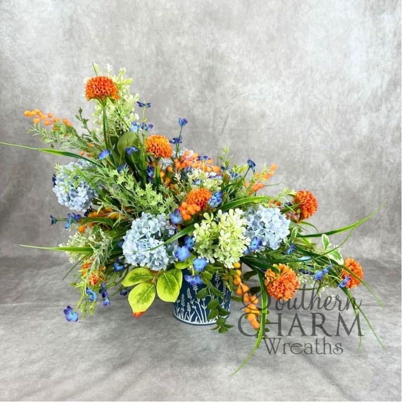 asymmetrical blue and orange hydrangea arrangement on gray background