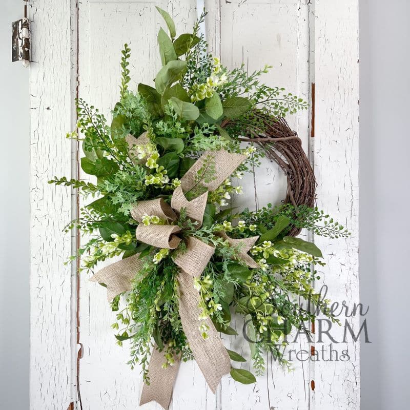 all greenery wreath with burlap bow on white door