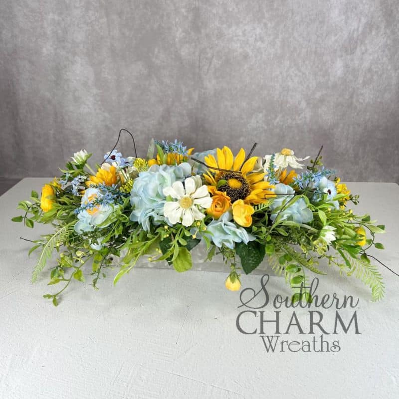 blue hydrangea and yellow sunflower arrangement on gray background