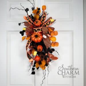 DIY Pumpkin Halloween Swag featuring pumpkins, candy accents, and harlequin ribbon displayed as festive door or lantern décor.