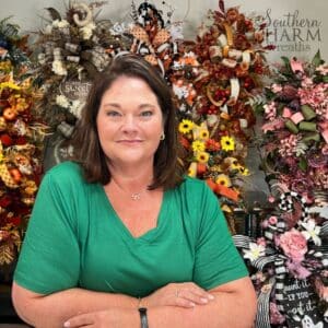 Julie Siomacco smiling in her craft room surrounded by ribbons and wreath supplies.