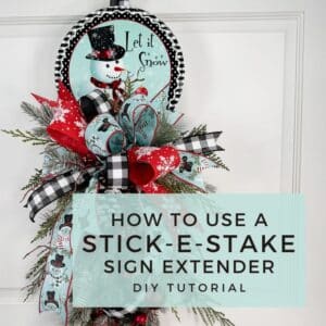 Let it Snow” snowman sign attached to holiday swag with plaid and snowflake ribbon using Stick-E-Stake Sign Extender technique.