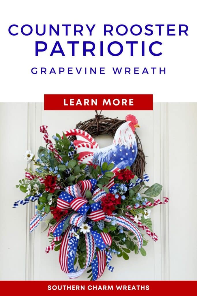 Country Patriotic Rooster Grapevine Wreath hanging on a white door, featuring a red white and blue rooster sign, layered patriotic ribbon bow, red geraniums, blue blossom clusters, and mixed greenery.