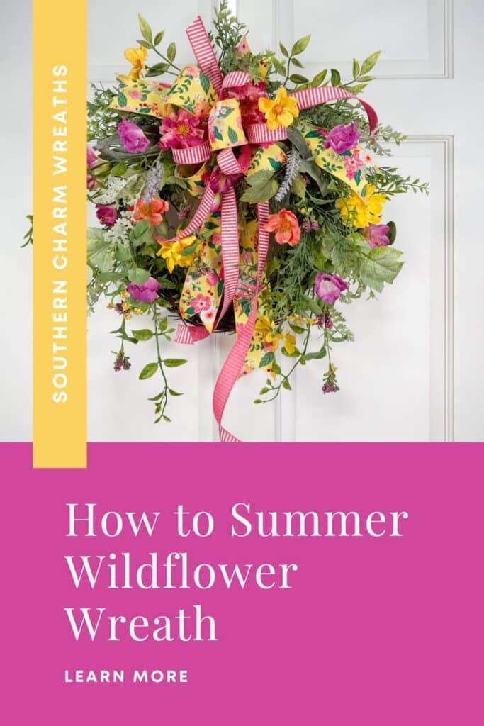 Summer wildflower wreath on a white paneled door featuring layered silk florals in hot pink, yellow, coral, orange, and purple, with trailing mixed greenery and a double-ribbon bow in yellow floral print and pink stripe at the top. A yellow vertical banner on the left reads Southern Charm Wreaths in white. A hot pink footer block at the bottom reads: How to Summer Wildflower Wreath, with a Learn More label below in white caps.