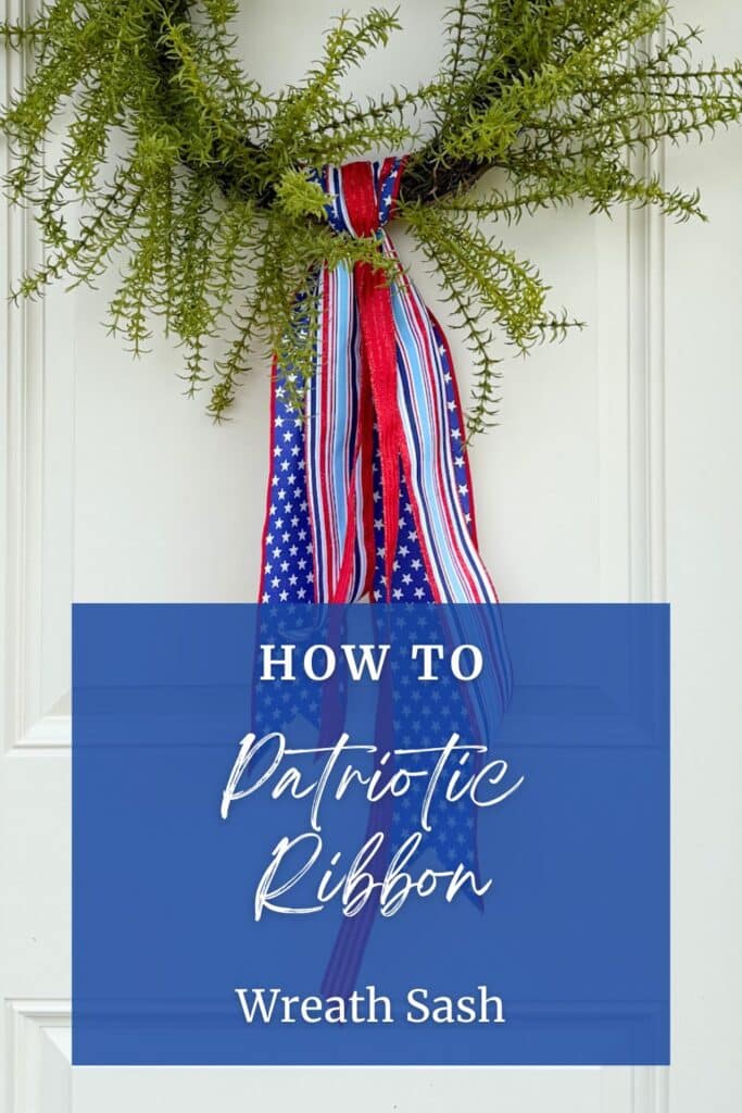 Front-facing view of a patriotic ribbon wreath sash on a full fern wreath on a white paneled door with gray siding. Three patriotic wired ribbon tails — wide navy star, medium red stripe, and narrow light blue stripe — hang from the bottom center of the wreath at slightly different lengths with dovetail-cut ends. White header text in navy reads: Patriotic Ribbon Wreath Sash. A red button bar reads: Learn More. Red footer bar reads: Southern Charm Wreaths in white.