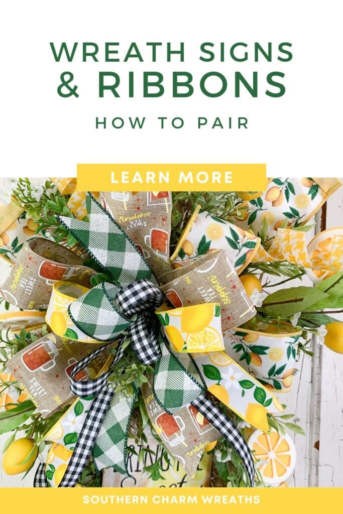 Overhead close-up of a multi-ribbon wreath bow on a grapevine wreath base against a whitewashed wood background. The bow features a wide lemon-print ribbon, a burlap sweet tea ribbon, a green plaid buffalo check, and a black and white buffalo check wired ribbon layered together, with mixed greenery visible around the edges. White background header in dark green reads: Wreath Signs and Ribbons, How to Pair. A yellow button bar reads: Learn More. Yellow footer bar reads: Southern Charm Wreaths in white.