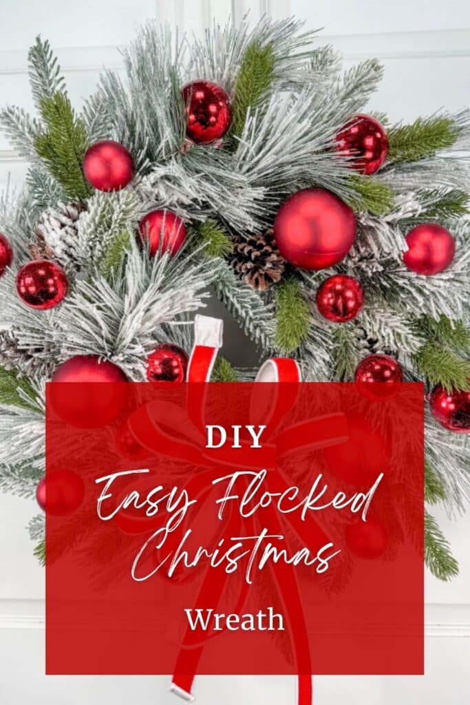 Close-up of a flocked pine Christmas wreath with red ball ornaments and a pine cone, behind a red text box that reads DIY Easy Flocked Christmas Wreath.