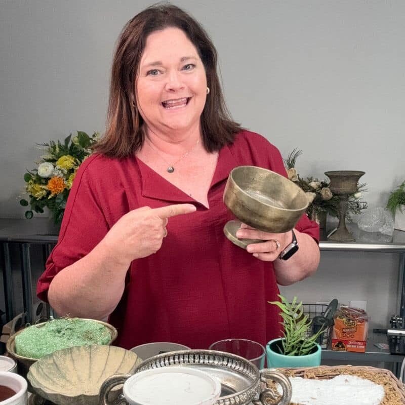 Julie pointing at a container for a silk flower arrangement.
