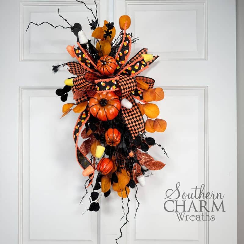 DIY Pumpkin Halloween Swag featuring pumpkins, candy accents, and harlequin ribbon displayed as festive door or lantern décor.