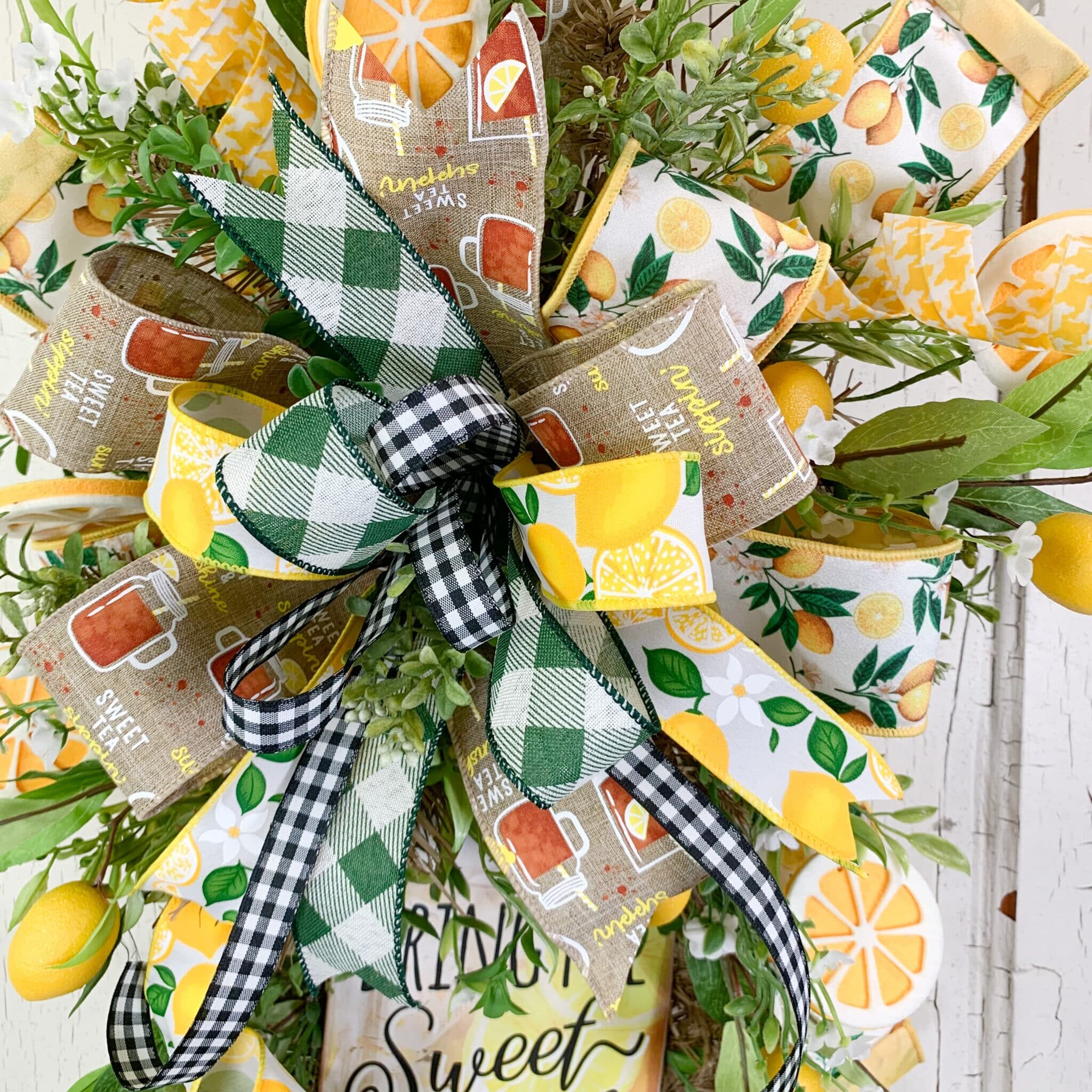 Close-up of a lemon and sweet tea themed wreath bow showing four coordinated wired ribbons - a lemon print, a burlap sweet tea ribbon, a yellow houdstooth, and a black and white buffalo check. All pulled from the wreath sign palette.